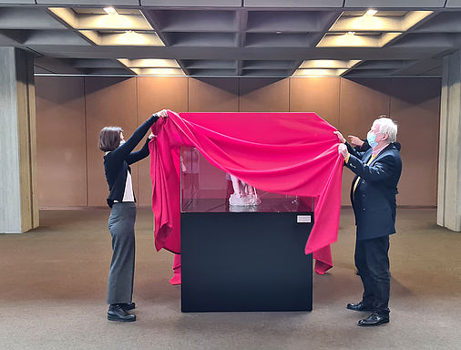 Prof. Dr. Susanne Leist, Dr. André Schüller-Zwierlein und Hans-Peter Riese enthüllen die Vitrine mit der Plastik