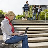 Studentin mit Laptop auf den Treppen vor dem zentralen Hörsaalgebäude