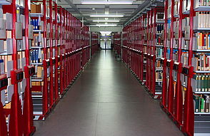 Das Bild zeigt das Magazin von der Uni-Bibliothek. Man sieht viele Regale mit Büchern in einem großen Raum.