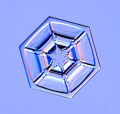 Hexagonaler Schneekristall in mikroskopischer Aufnahme