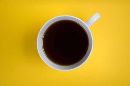 Bild: Kaffeetasse mit Kaffee von oben auf gelbem Untergrund