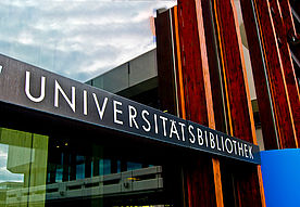 Das Bild zeigt das Schild über dem Eingang von der Uni-Bibliothek. Darauf steht Universitätsbibliothek.