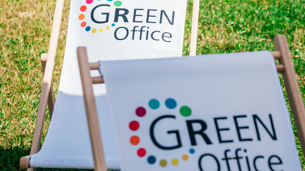 Liegestühle mit dem Logo des "Green Office" der Universität Regensburg stehen auf einer grünen Wiese.