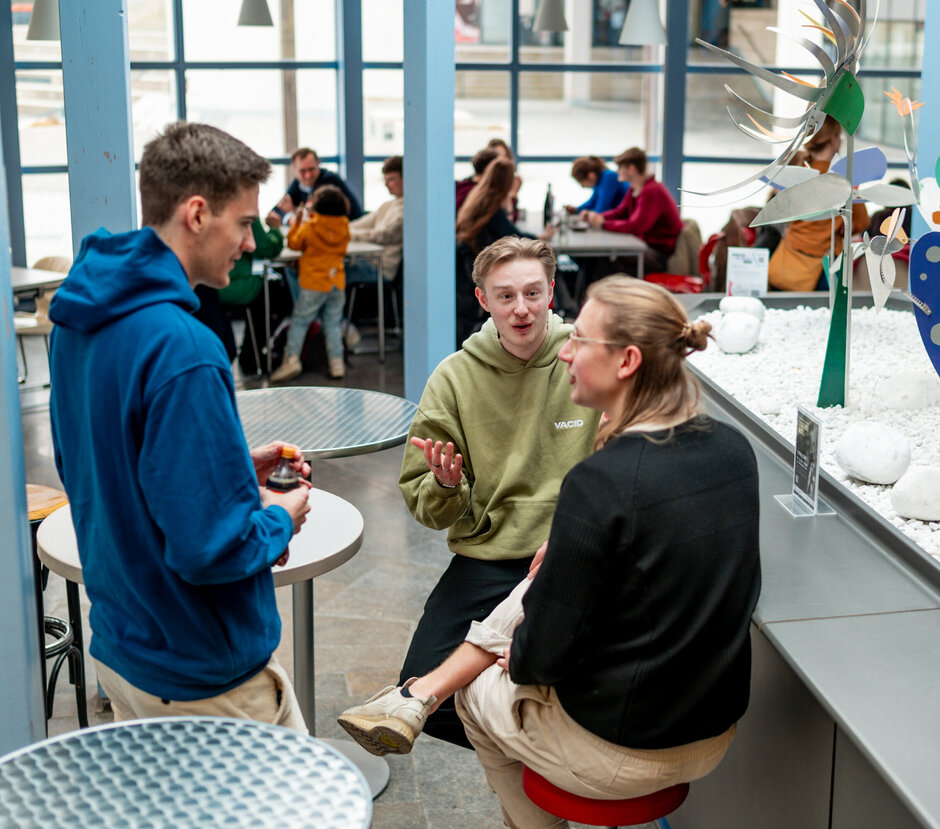 Drei Studenten unterhalten sich in einer Cafeteria an der Universität Regensburg