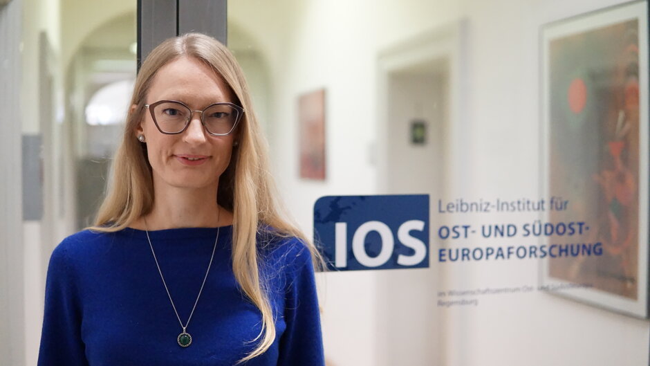 Frau mit Brille vor Glastür, die den Schriftzug "IOS - Leibniz-Institut für Ost- und Südosteuropaforschung" trägt