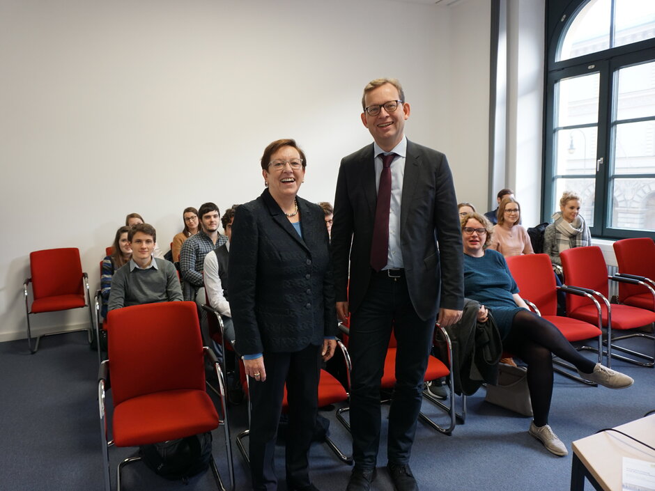 Die Präsidentin des LSG, Elisabeth Mette, und Prof. Kingreen stehen in einem Seminarraum. Hinter ihnen sitzen die Teilnehmer/-innen der Exkursion. (öffnet Vergrößerung des Bildes)