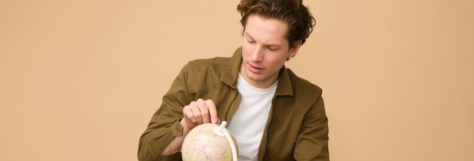 Junger Mann betrachtet kleinen Globus