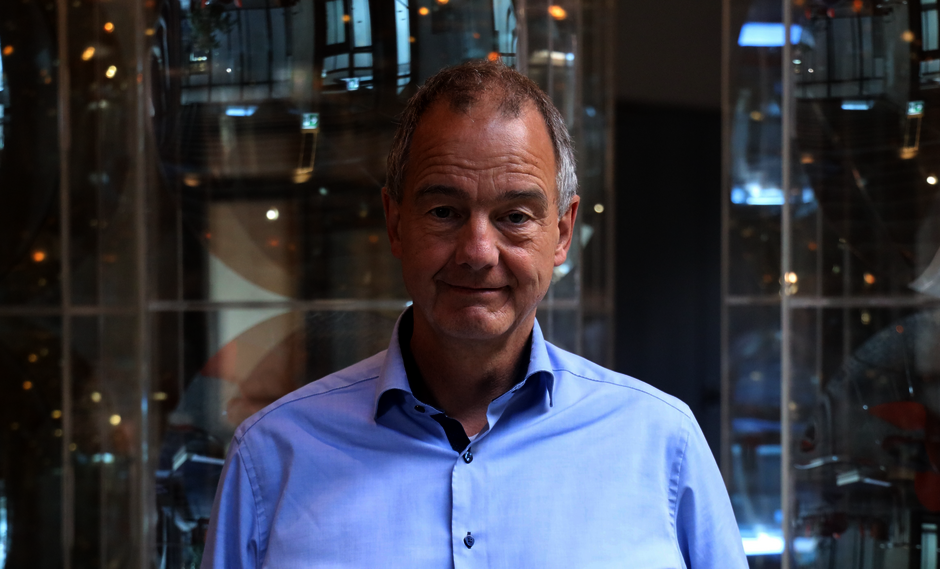 Porträtfoto: Herr in hellblauem Hemd vor neutralem Hintergrund