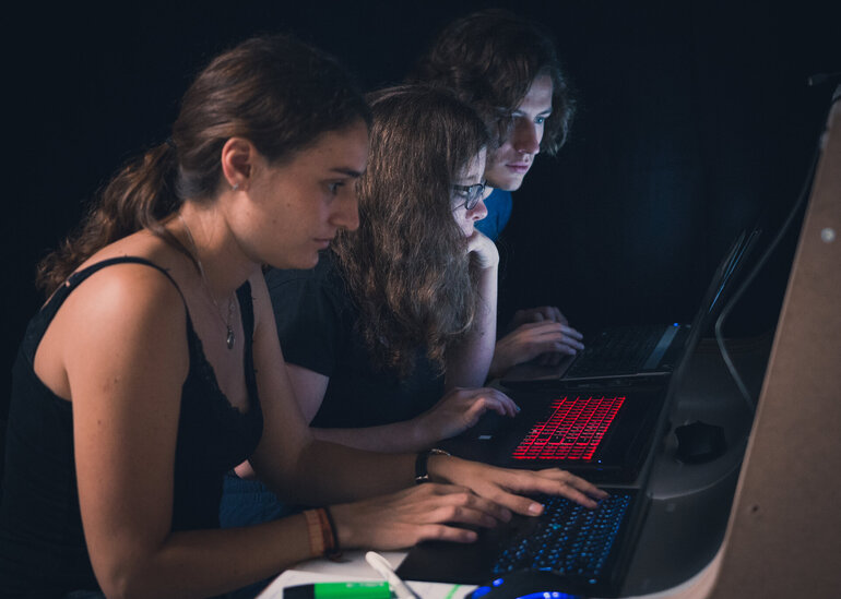 Studierende sitzen vor ihren Laptops und programmieren.