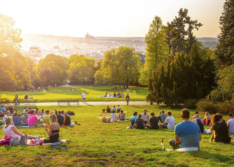 sunset in Rieger Gardens, Riegrovy sady, in Prague. Many people sitting in the grass and enjoying sunny summer evening and lookout of Prague historical city centre. Czech Republic