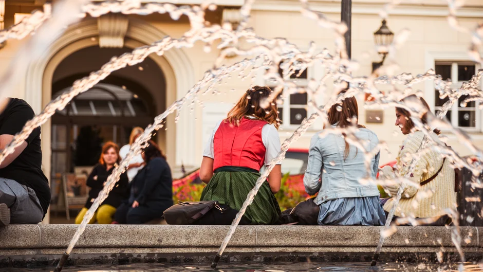 Junge Menschen sitzen in ein Gespräch vertieft am Rand eines Springbrunnens (öffnet Vergrößerung des Bildes)