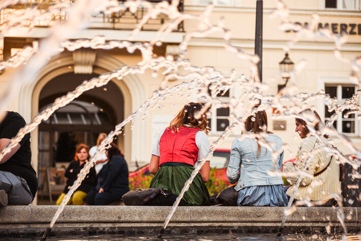 Junge Menschen sitzen in ein Gespräch vertieft am Rand eines Springbrunnens (öffnet Vergrößerung des Bildes)