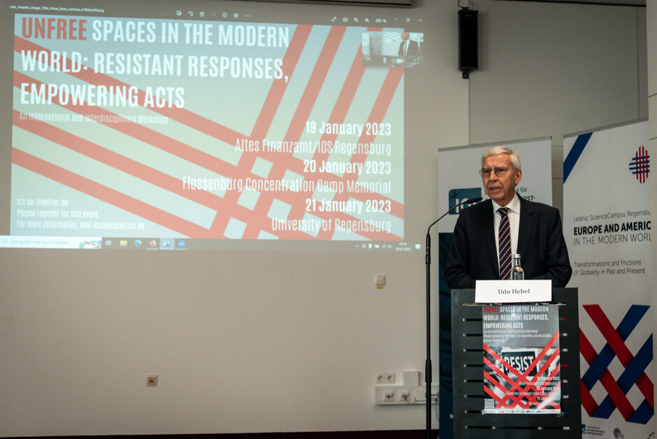 UR-Präsident Prof. Dr. Udo Hebel eröffnet - an einem Rednerpult stehend - die Konferenz.