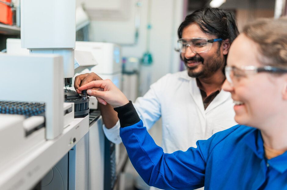 Zwei junge Forschende, die einen Chemieversuch durchführen.