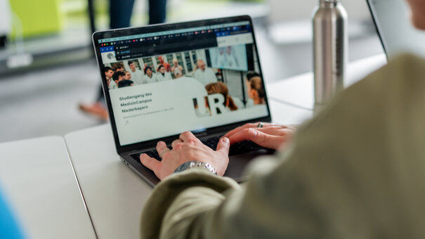 Ein Student sitzt am Laptop, seine Hände bedienen die Tastatur.