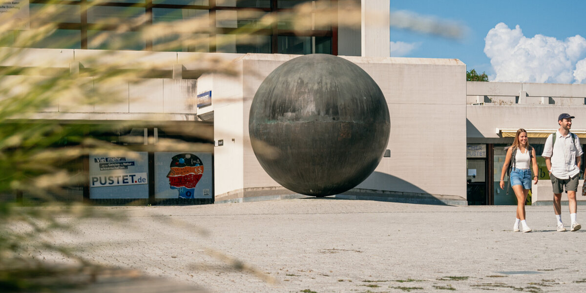 Studierende gehen über das Forum am Campus der Universität Regensburg. 