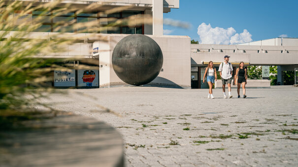 Studierende gehen über das Forum am Campus der Universität Regensburg. 