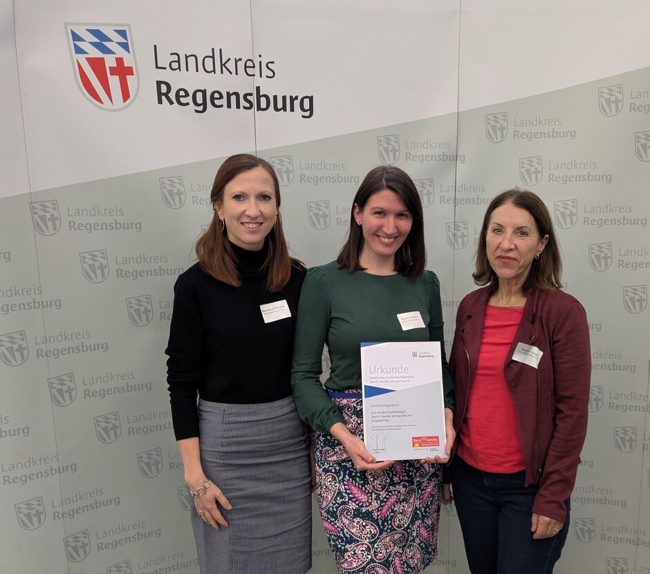 Drei Frauen stehen vor einer grauen Wand und haben eine Urkunde in der Hand. (öffnet Vergrößerung des Bildes)