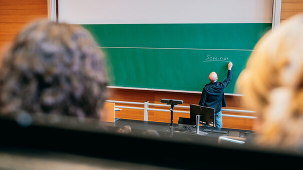 Ein Dozent bei der Tafelanschrift in einem Hörsaal der Universität Regensburg.