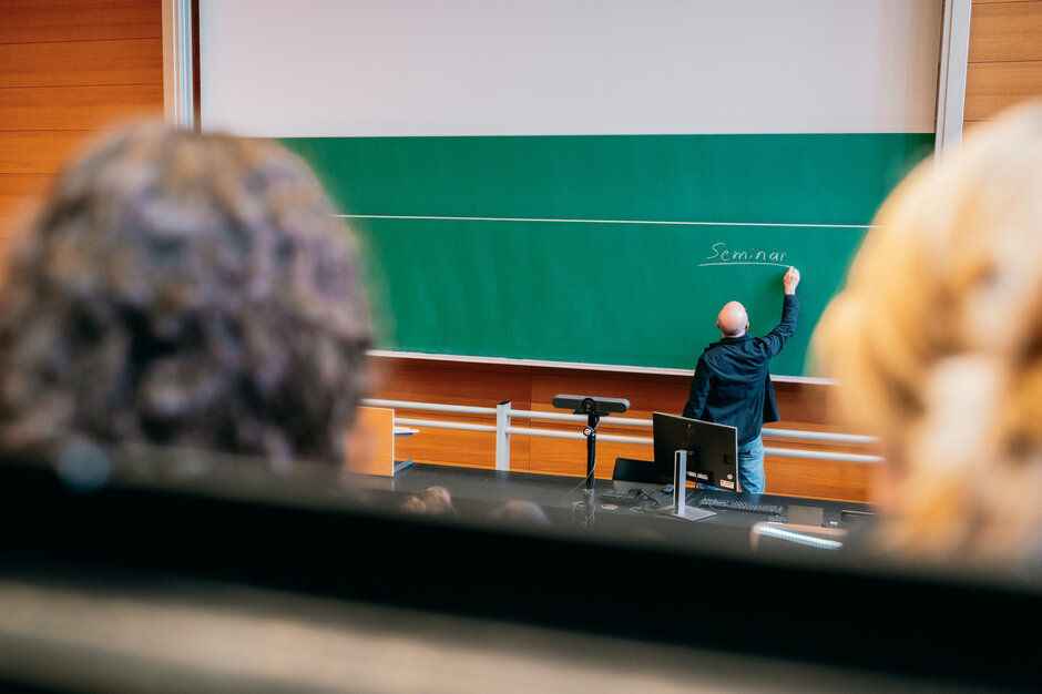 Ein Dozent bei der Tafelanschrift in einem Hörsaal der Universität Regensburg.