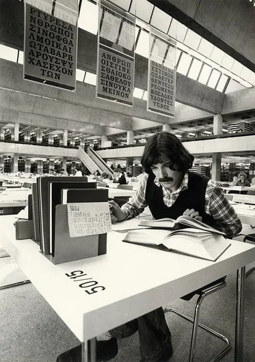 Buchstaben und Texte hängen als Banner von der Decke, im Vordergrund Studierender mit Büchern (öffnet Vergrößerung des Bildes)