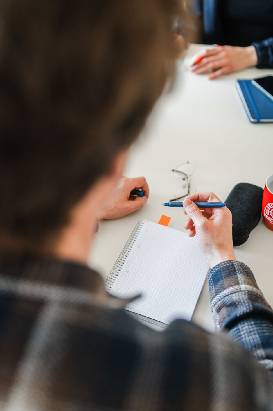 Person schreibt etwas in einen Notizblock