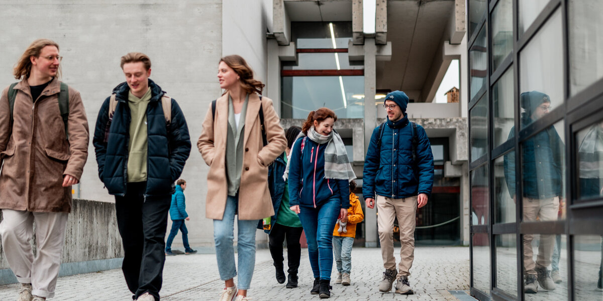 Zwei Gruppen von Studierenden gehen über den Campus der Universität Regensburg.
