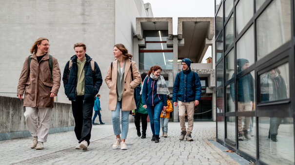 Zwei Gruppen von Studierenden gehen über den Campus der Universität Regensburg.
