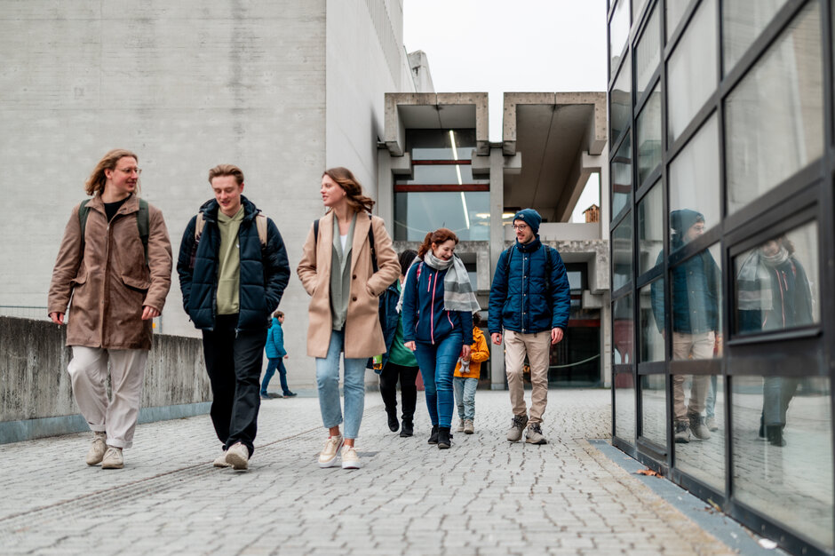 Zwei Gruppen von Studierenden gehen über den Campus der Universität Regensburg.