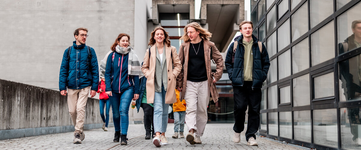 Eine Gruppe von Studierenden gehen über den Campus der Universität Regensburg.