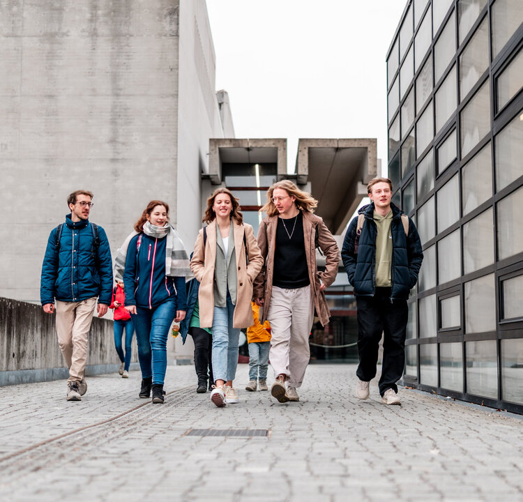 Eine Gruppe von Studierenden gehen über den Campus der Universität Regensburg.