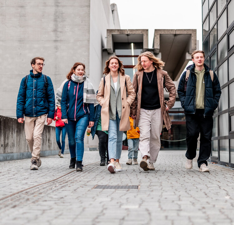 Eine Gruppe von Studierenden gehen über den Campus der Universität Regensburg.