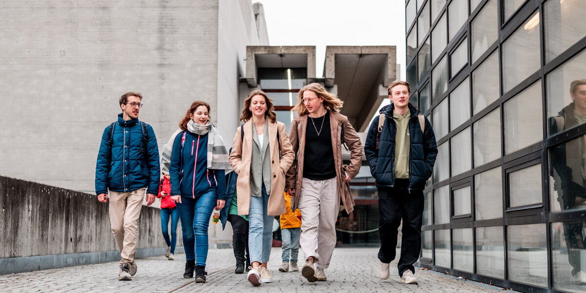 Eine Gruppe von Studierenden gehen über den Campus der Universität Regensburg.