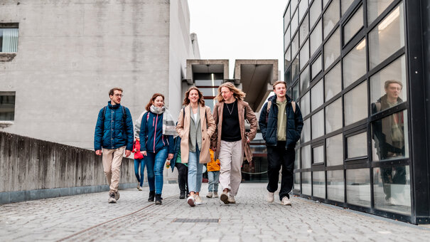 Eine Gruppe von Studierenden gehen über den Campus der Universität Regensburg.