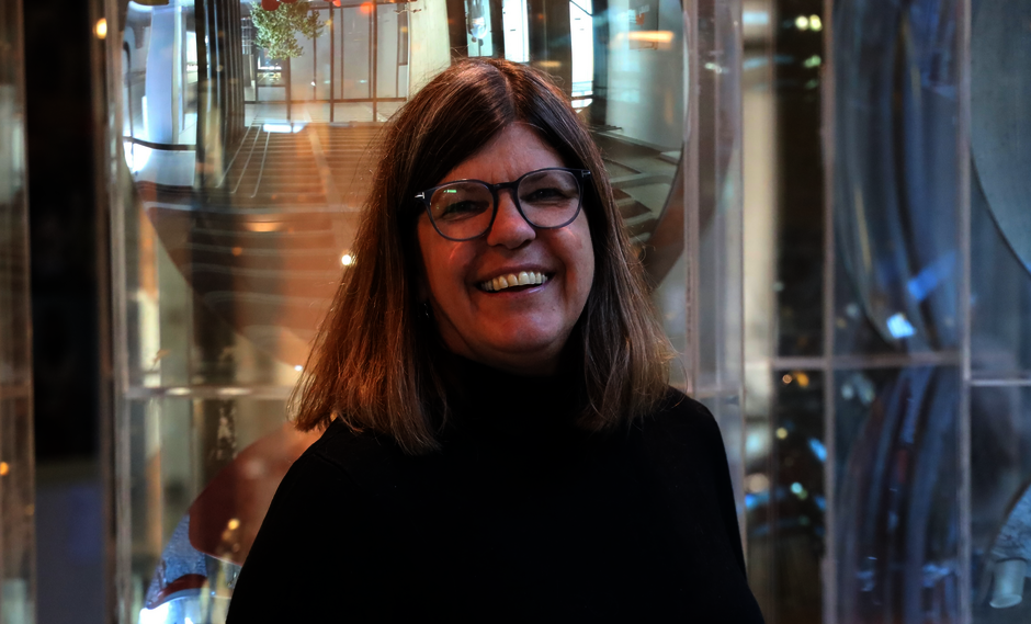 Porträtfoto: Frau mit Brille und schulterlangen, glatten Haaren vor neutralem Hintergrund