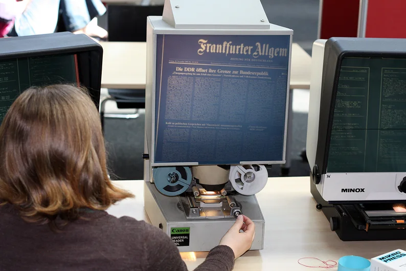 Frau bedient Lesegerät für Mikrofilm (öffnet Vergrößerung des Bildes)