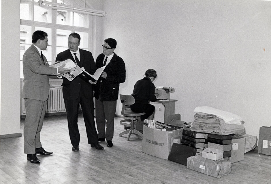 Bibliotheksdirektor Dr. Max Pauer (Mitte) mit seinen ersten Mitarbeitern in den noch fast leeren Räumen der Ausweichstelle im Thon-Dittmer-Palais (öffnet Vergrößerung des Bildes)