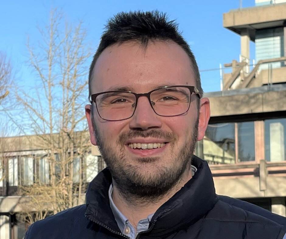 Ein Mann mit Brille blickt lächelnd in die Kamera.