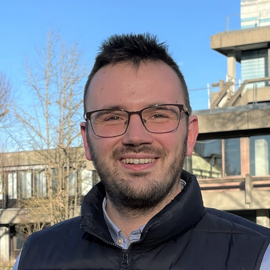 Ein Mann mit Brille blickt lächelnd in die Kamera.