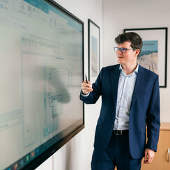 Ein Professor erklärt ein Schaubild auf einer elektronischen Tafel.