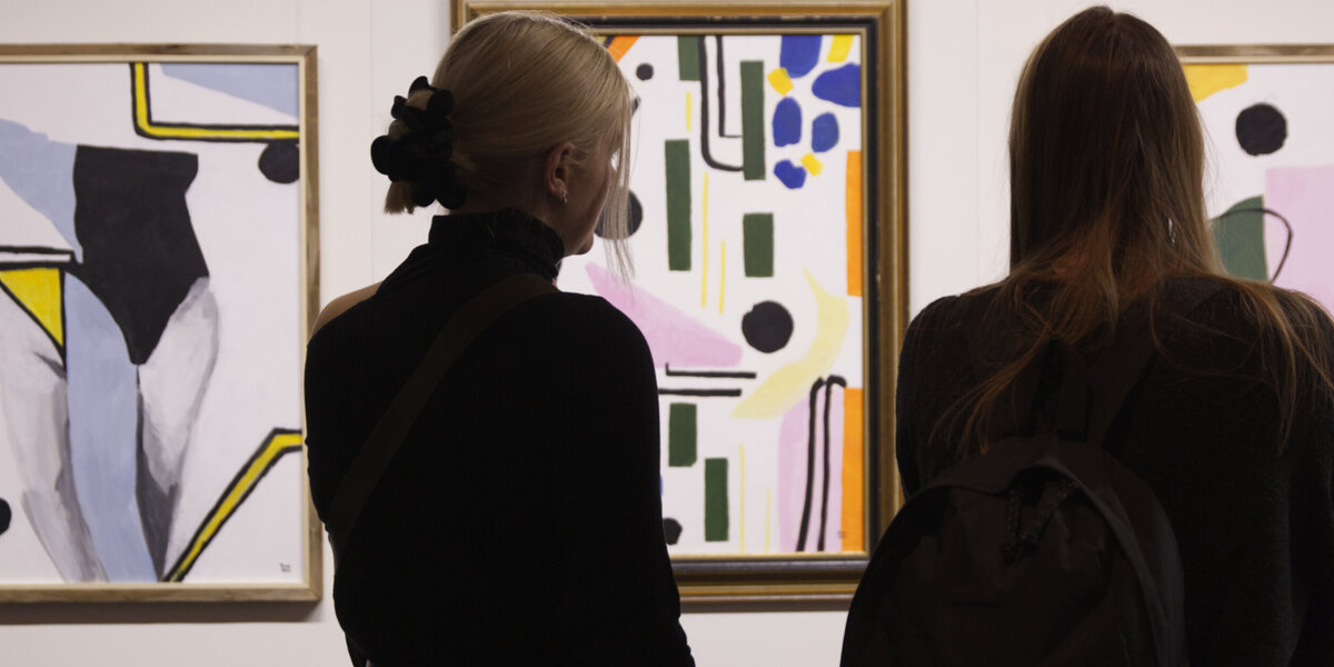 Zwei Frauen betrachten abstrakte Kunstwerke.