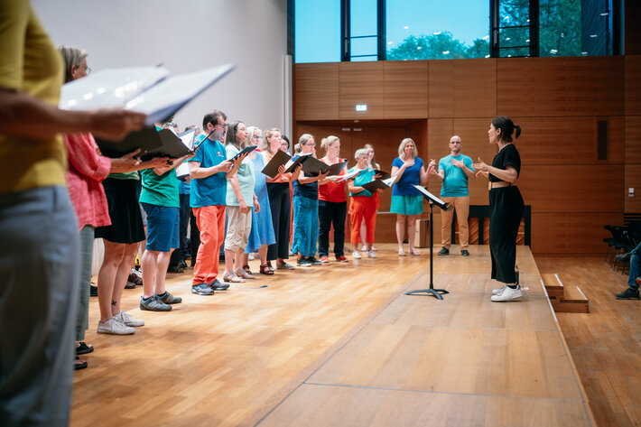 Bunt gekleidete, singende Menschen von der Seite. (öffnet Vergrößerung des Bildes)