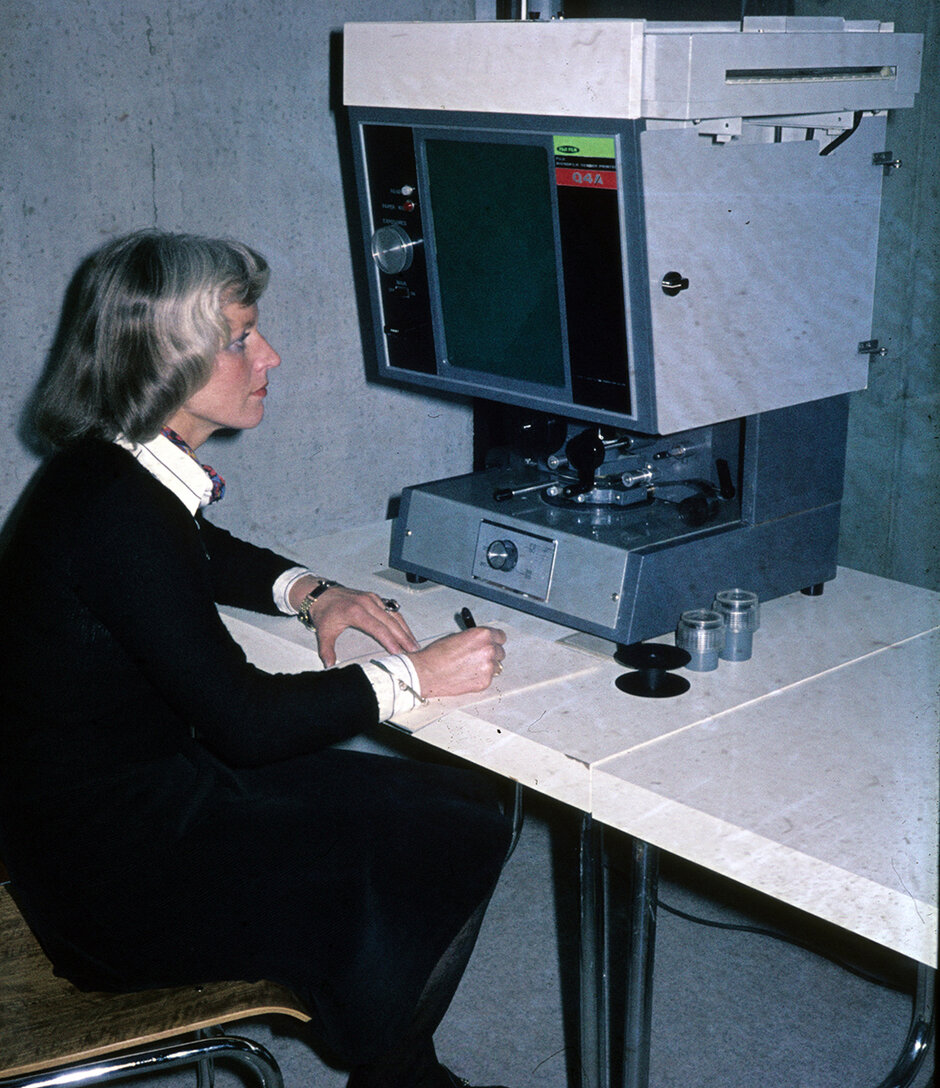Frau sitzt schreibend am Microfilm-Lesegerät (öffnet Vergrößerung des Bildes)