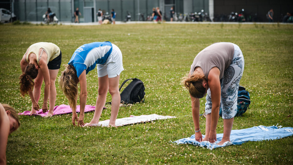 Drei Personen, die Yoga auf der Campuswiese der Uni Regensburg machen
