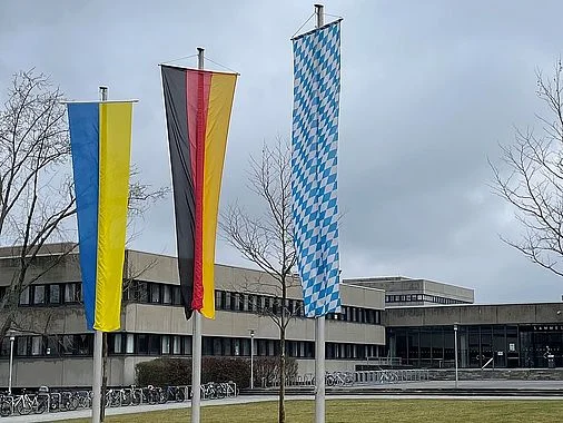 Bild der ukrainischen, deutschen und bayerischen Flagge vor der Universität Regensburg.