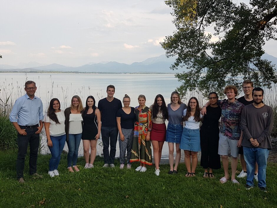 Gruppenfoto aller Teilnehmenden mit Prof. Kingreen auf einer Wiese am Ufer des Chiemsees mit den Alpen im Hintergrund. (öffnet Vergrößerung des Bildes)