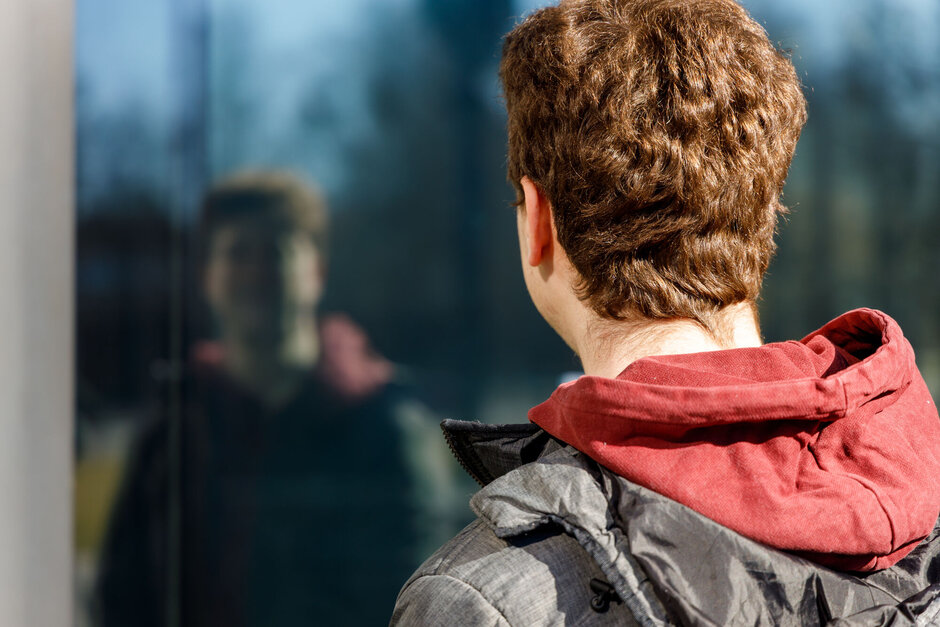 Student, der sich in einer Scheibe spiegelt