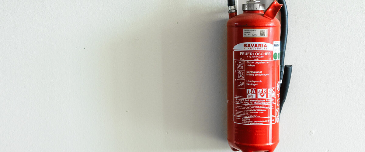 Feuerlöscher, der an einer weißen Wand hängt