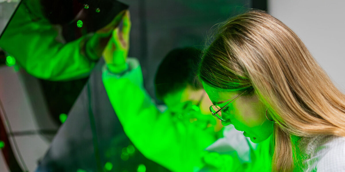 Junge Forschende, die über einem Laserexperiment steht.