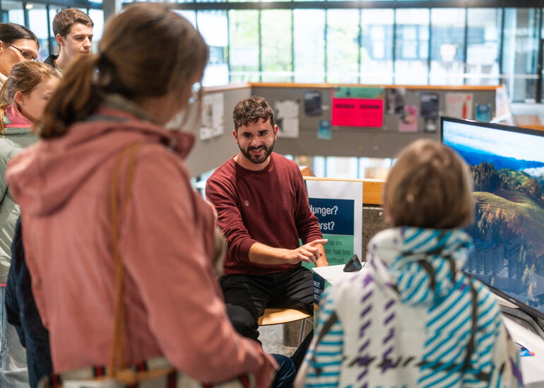 Ein Wissenschaftler im Gespräch mit interessierten Gästen bei der Wissenschaftsnacht an der Universität Regensburg.